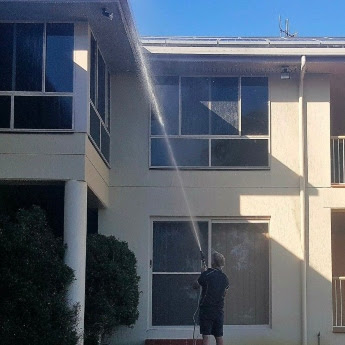 A The Exterior Group technician using a pressure washer to reach high areas on a home.