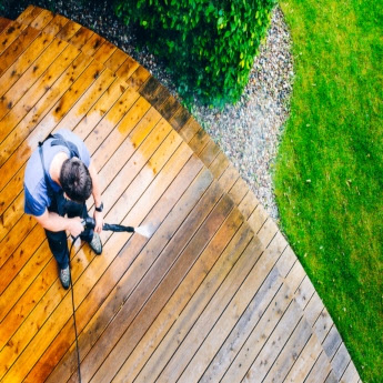 A The Exterior Group technician using a professional-grade pressure washer next to a pool