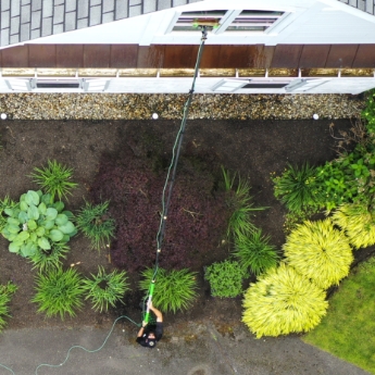 A The Exterior Group technician using a high-end water-fed pole to clean second story windows.