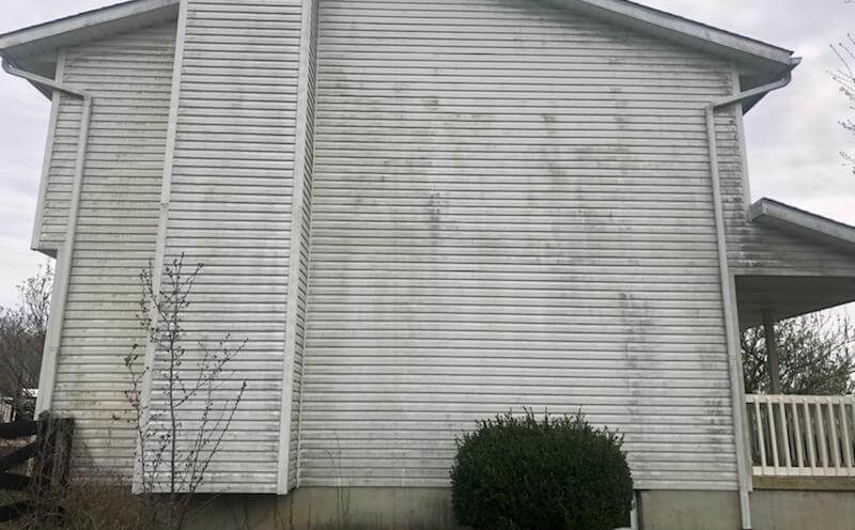 Dirty siding on a white two-story house with a chimney. Dirty siding on a white two-story house with a chimney.